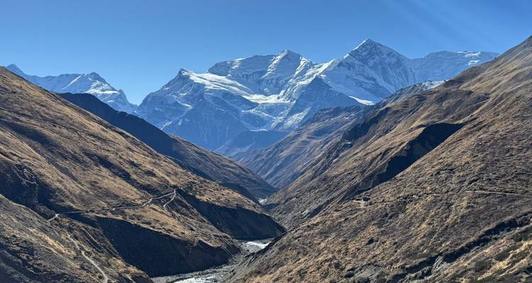 Valley with a winding river and snow-capped mountains in the distance.