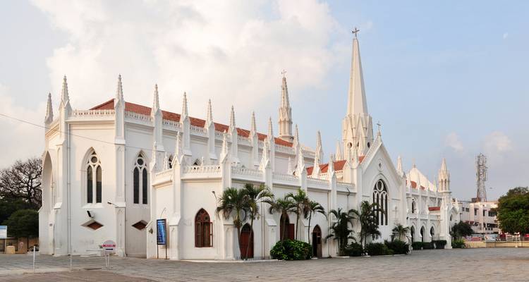 A beautiful white church with gothic architecture and palm trees in front.