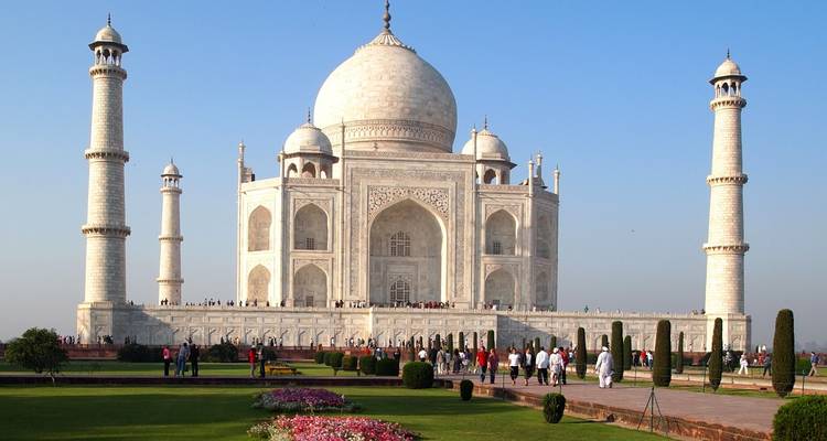 The Taj Mahal with people in front, set against a clear blue sky.