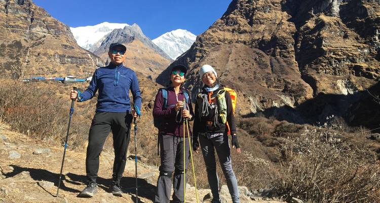 Three hikers posing on a trail with dramatic mountain scenery.