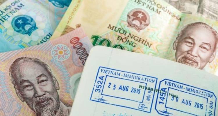 Vue rapprochée de la monnaie vietnamienne et d'un passeport avec des tampons d'immigration.