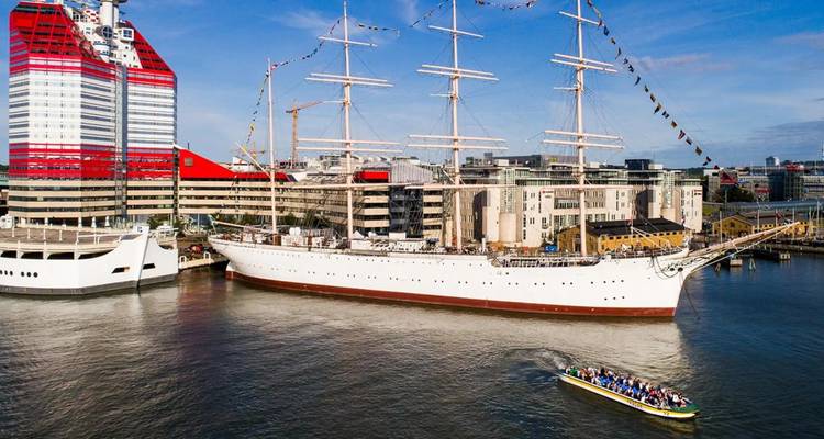 A large sailing ship docked in a city harbor.
