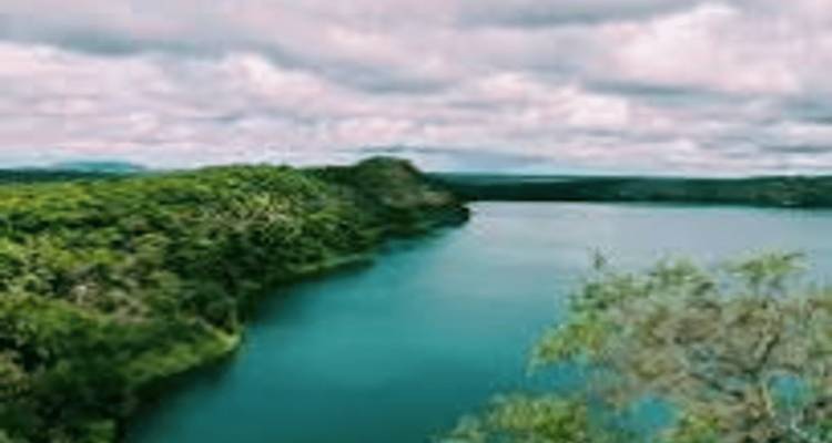Image floue d'un lac avec de la verdure environnante et un ciel nuageux.