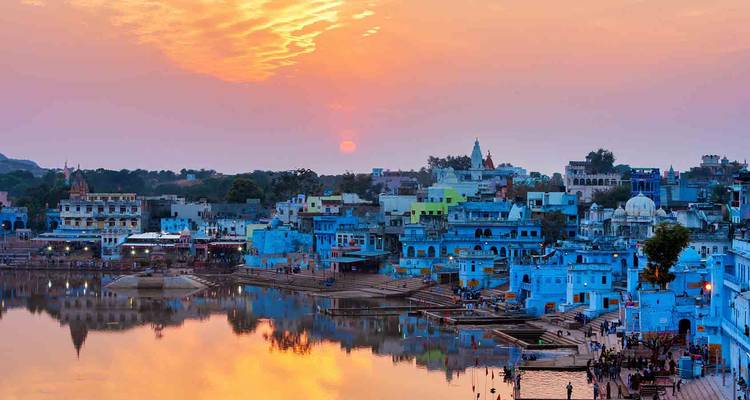 A picturesque view of a city by a lake during sunset.