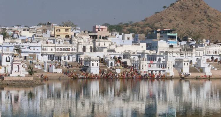 A city situated by a lake with mountainous background.