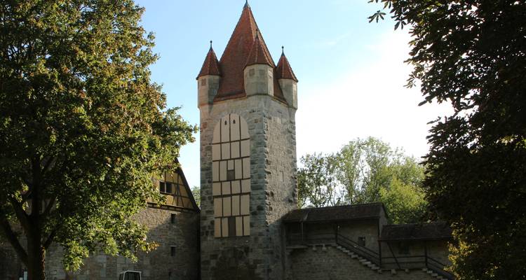 Tour historique et murs avec des arbres au premier plan.