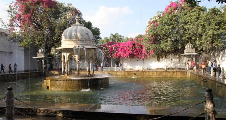 Une fontaine d'eau entourée de verdure et de fleurs.