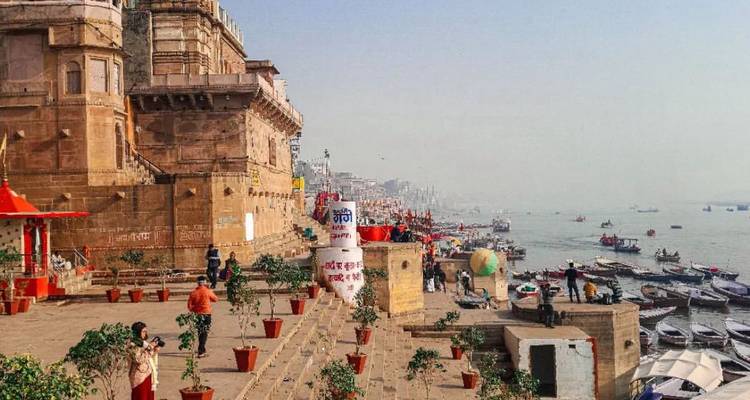 Ghats de Varanasi con barcas y gente cerca del Ganges.