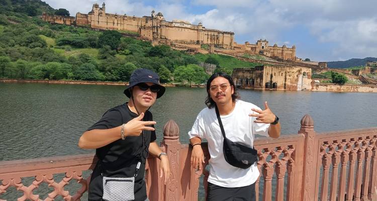 Dos hombres posando con un fuerte y agua al fondo.