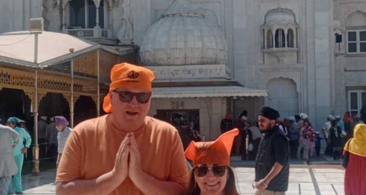Zwei Personen in orangen Turbanen vor einer Tempelstruktur.