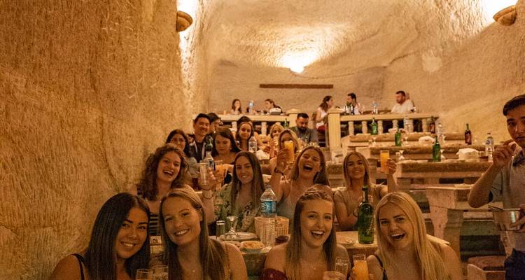Group of people enjoying a meal in a cave-like setting.