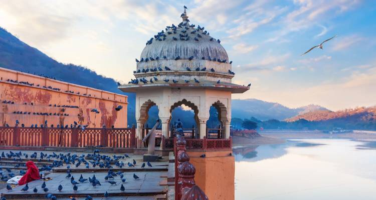 Birds on a pavilion by a scenic lake.