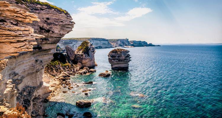 Falaises côtières spectaculaires avec une eau bleue claire et des formations rocheuses.