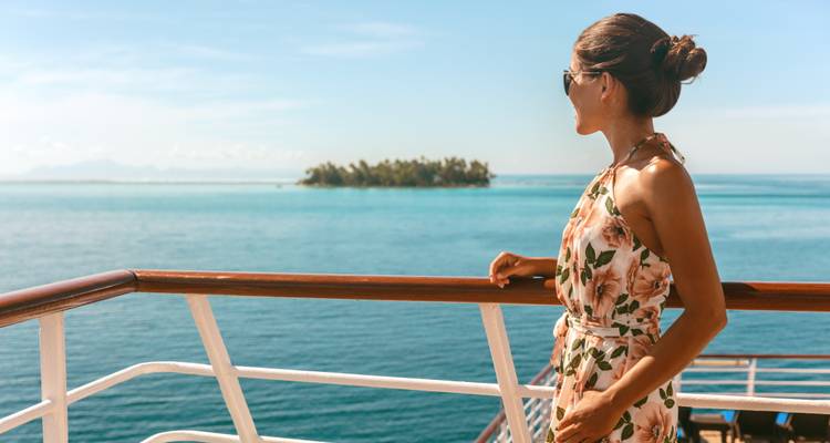 Femme debout sur le pont d'un bateau surplombant la mer.