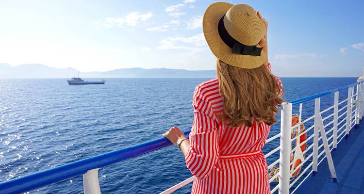 Femme regardant la mer depuis un bateau, portant un chapeau.