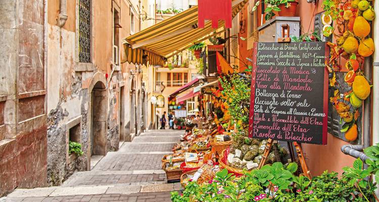 A colorful market street in a historic Italian town.