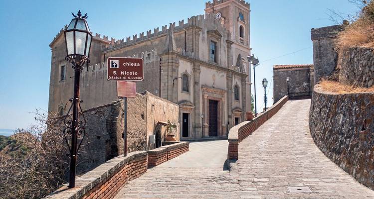 A historic church on a hill with a sign in Italian.