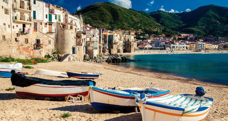 Plage pittoresque avec des bateaux colorés et une ville côtière.
