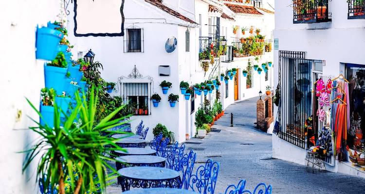 Rue charmante avec des pots de fleurs colorés et des chaises en métal à Mijas.