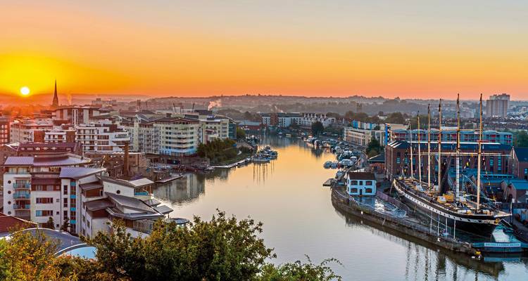 View of a river in a city at sunset with boats and buildings.