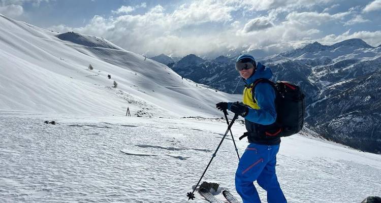 Skier on a snowy slope with a panoramic view of mountains in the background.
