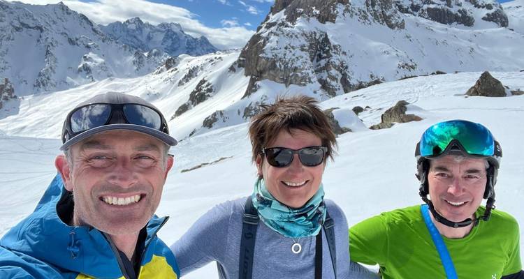 Three people posing for a photo on a snowy mountain background.