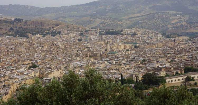 Vue panoramique d'une ville nichée au milieu de collines ondulantes.