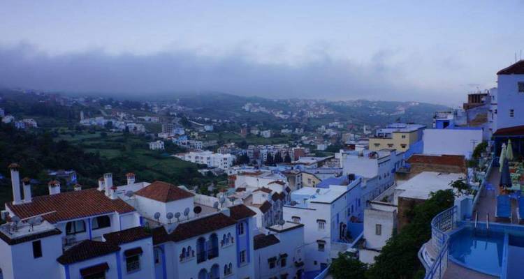 Vue de la ville avec des bâtiments peints en bleu et un arrière-plan montagneux.