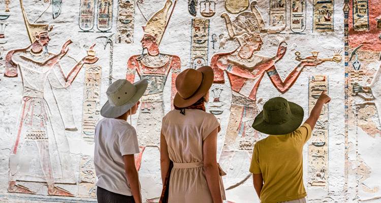 People observing ancient Egyptian carvings in a tomb.