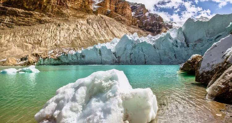 A turquoise glacial lake surrounded by icy cliffs.