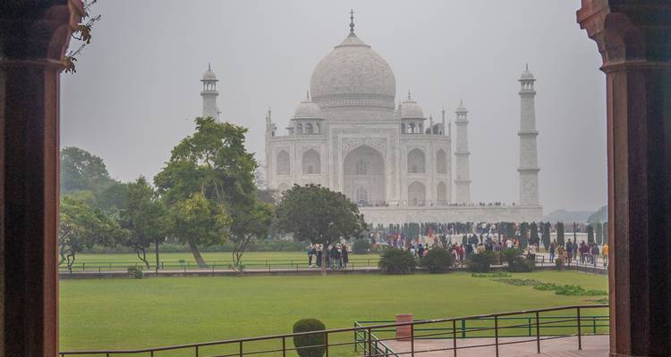 Taj Mahal with visitors walking in the foreground, surrounded by gardens.