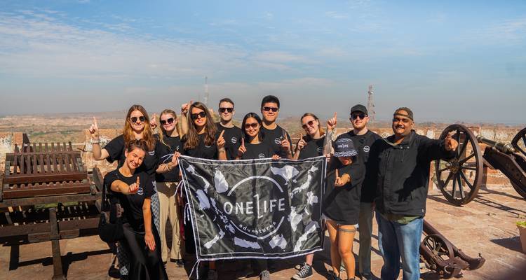 Group of people posing with a flag in front of cannons on a fort.