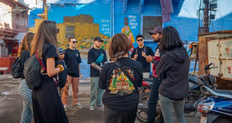 Group of people on a street tour with guide, near a blue wall mural.