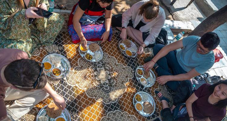 Group of people sitting on the ground sharing a traditional meal.