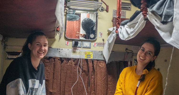 Two people with friendly expressions inside a train compartment.