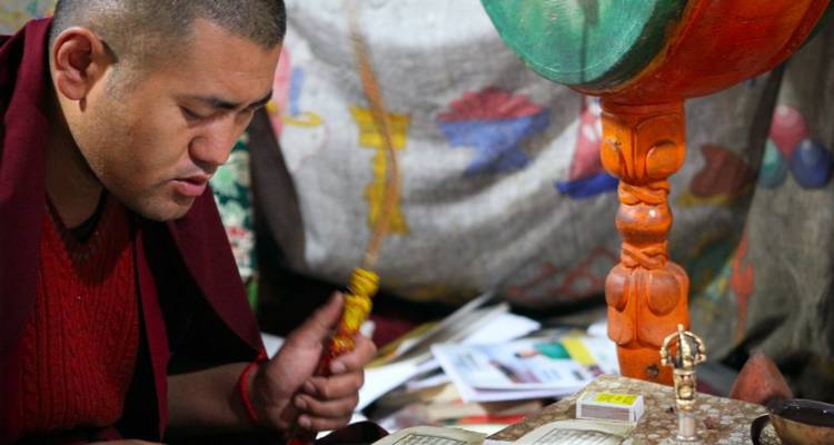 Moine pratiquant un rituel religieux avec des décorations colorées autour.