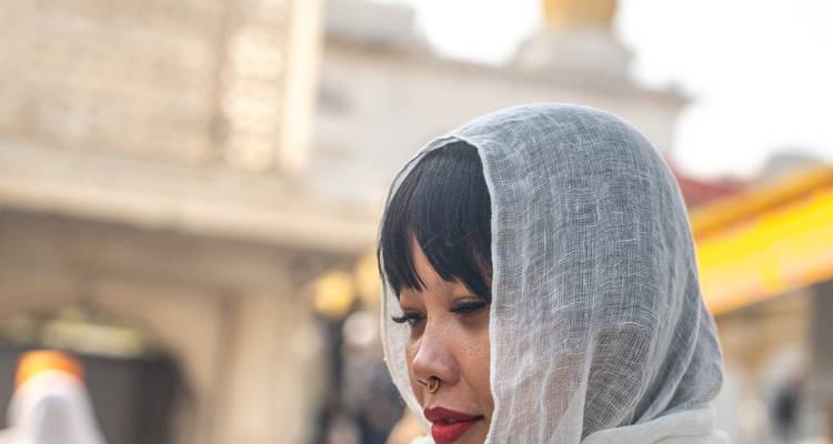 Person in a scarf standing in front of a historic monument.