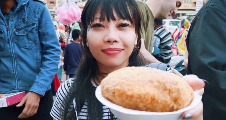 Person holding a snack in a busy market environment.