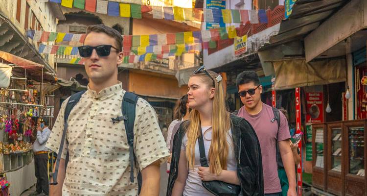 Tourists exploring a bustling market street with colorful flags.