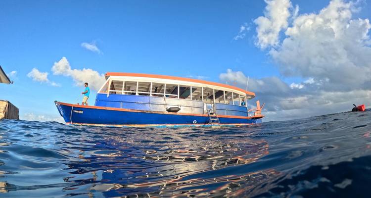 Bateau sur eau claire avec une personne debout dessus, sous un ciel bleu.