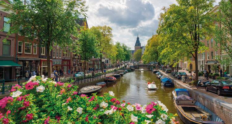 Busy canal scene with people, boats, and trees.