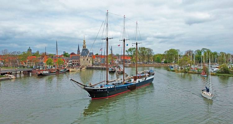 Navire historique naviguant dans un port avec des bâtiments traditionnels.
