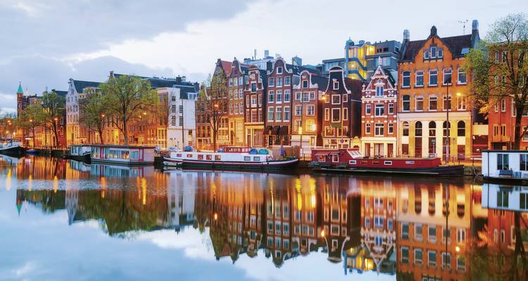 Canal bordé de bâtiments historiques et de bateaux se reflétant dans l'eau.