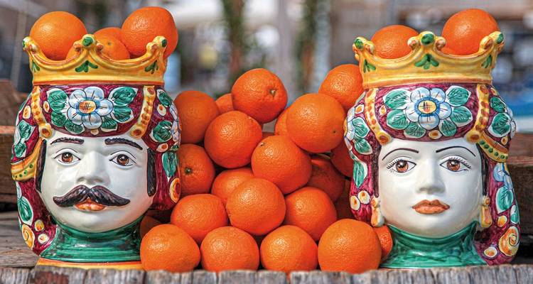 Ceramic heads among oranges on display.