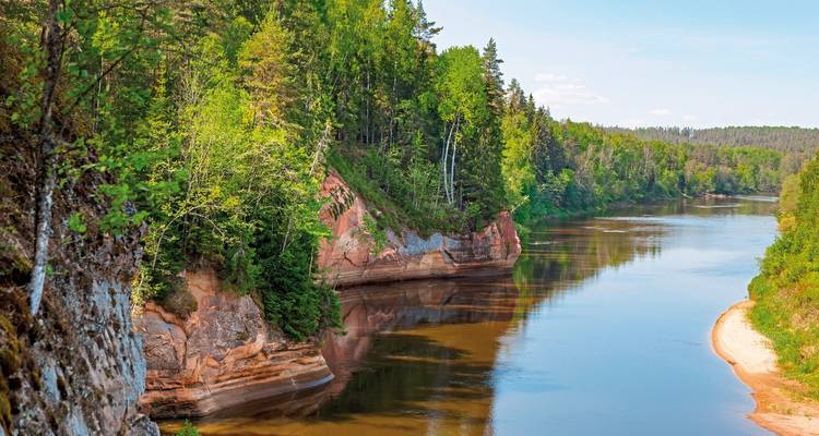 Malerischer Flussblick mit üppigem Grün und roten Felsen.