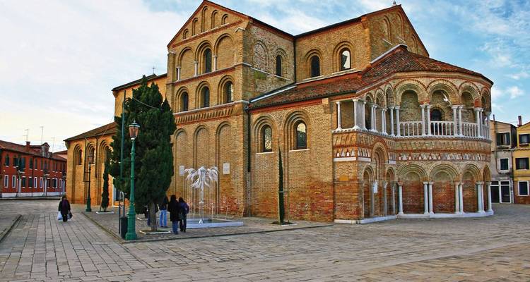 Romanesque basilica in the square with people around.