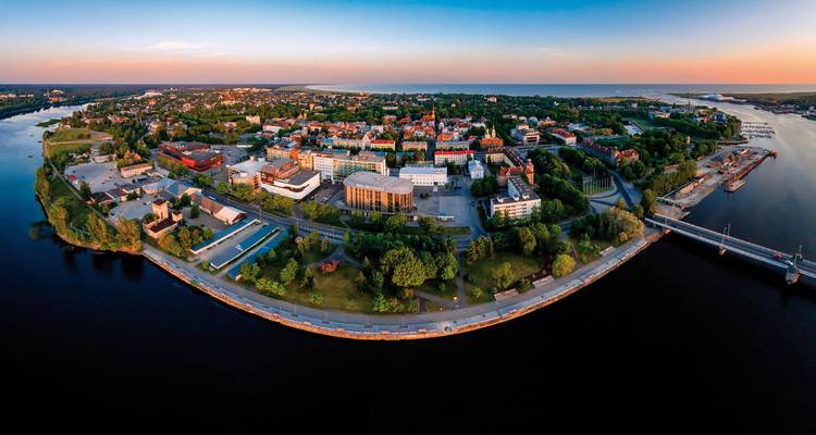 Aerial view of a river bend in a scenic cityscape during sunset.