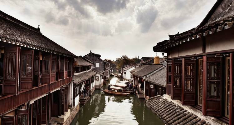 Ville d'eau traditionnelle avec des bateaux et de vieux bâtiments le long d'un canal.