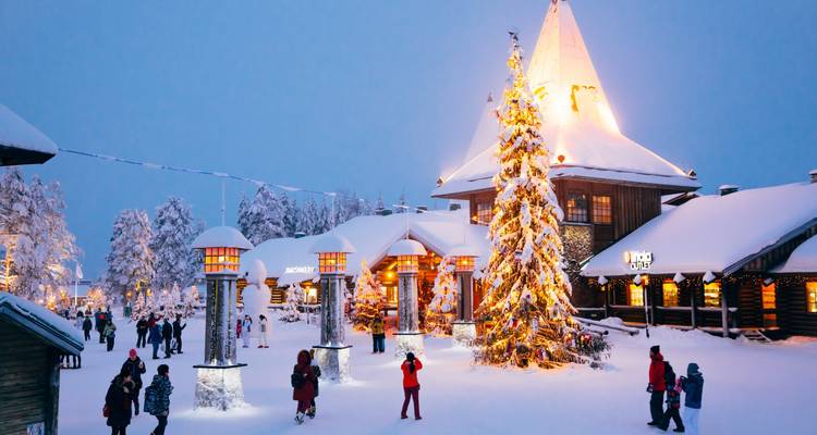 Weihnachtsdorf im Schnee mit einem großen geschmückten Baum.