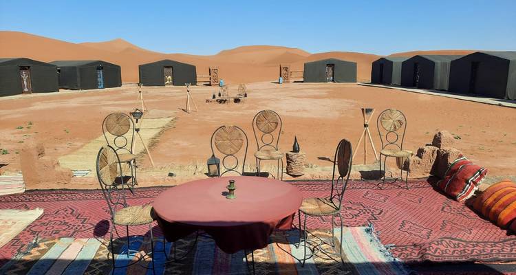 Outdoor dining area setup with tents in a desert landscape.